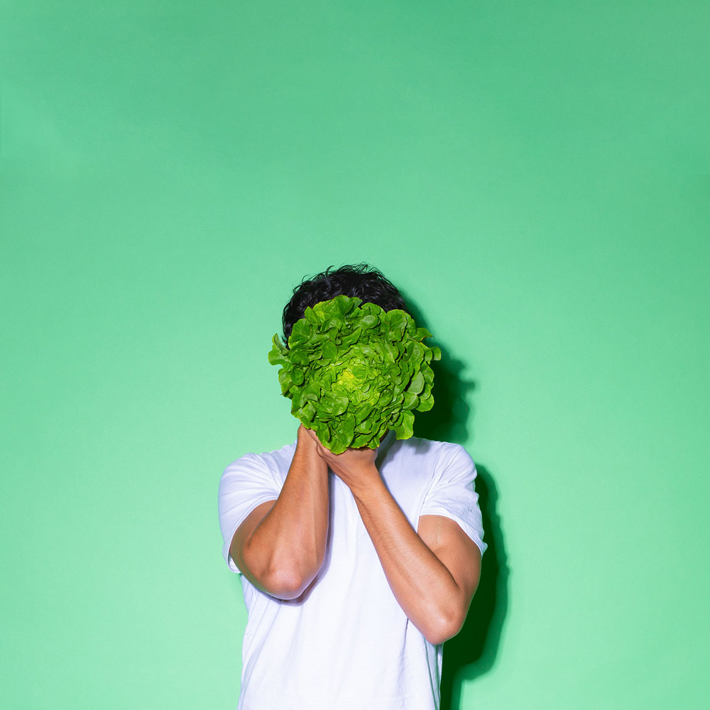 Mann mit Kopfsalat vor Gesicht